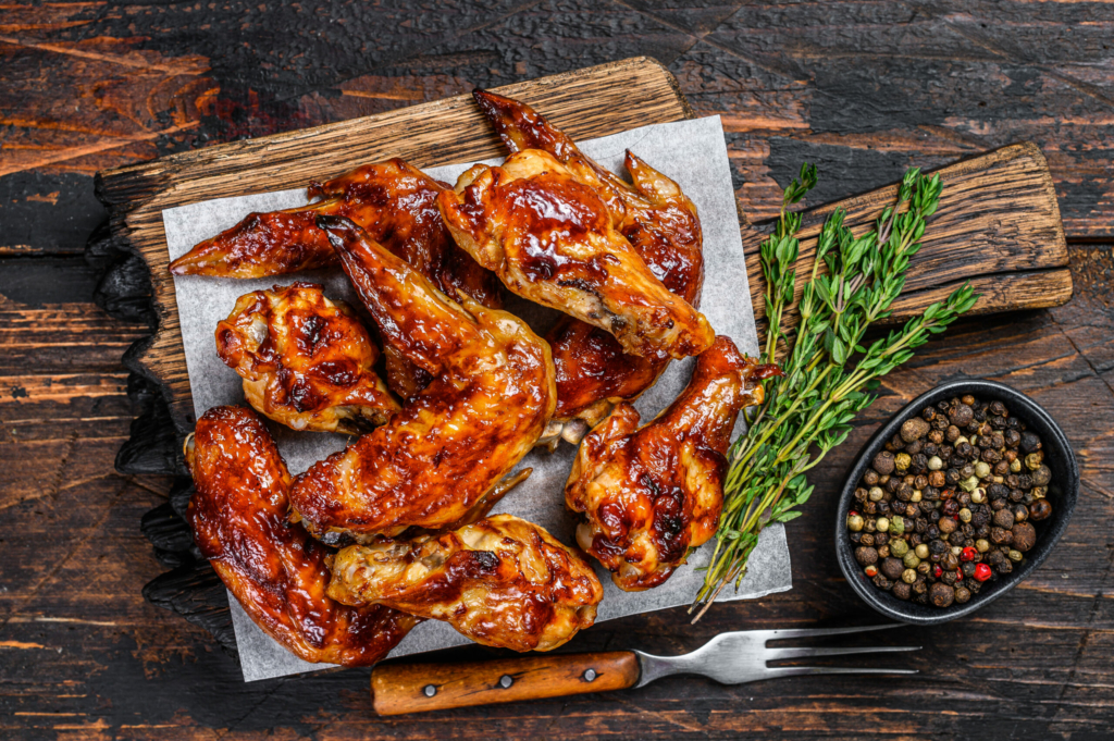 Baked Bbq chicken wings  with dip sauce. Dark wooden background. Top view.