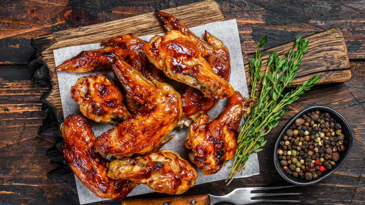Baked Bbq chicken wings  with dip sauce. Dark wooden background. Top view.